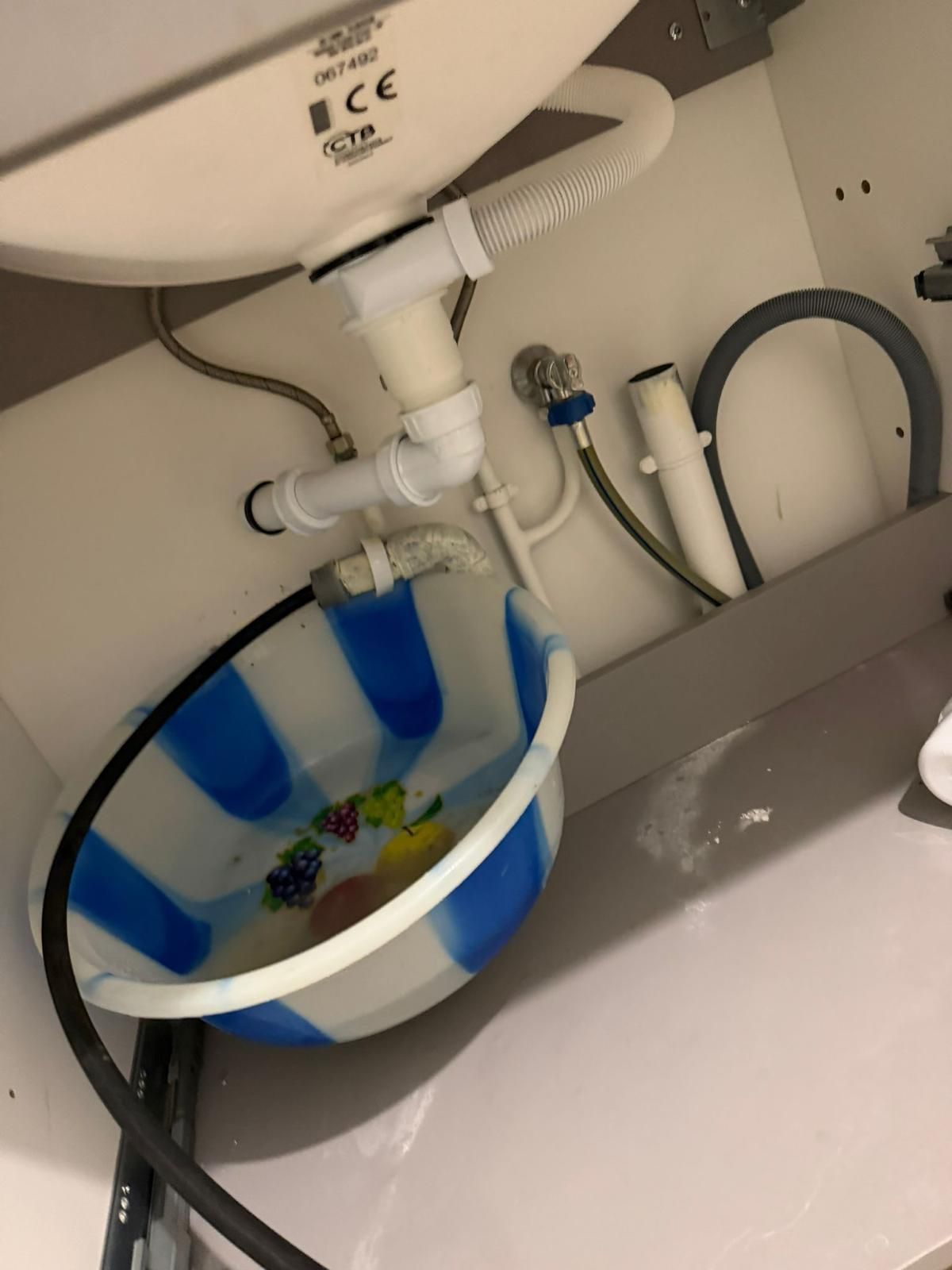 Fuite sous un évier, siphon et bassine de récupération